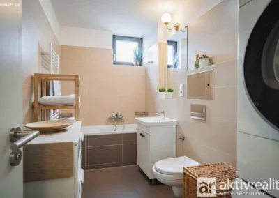 Moderní koupelna s vanou, umyvadlem a místem pro pračku a sušičku v bytě 3+kk.