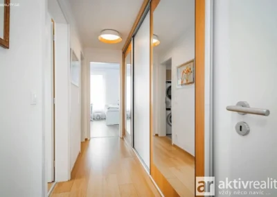 Prostorná vstupní chodba s vestavěnou šatní skříní v moderním bytě 3+kk v Nových Chabrech.